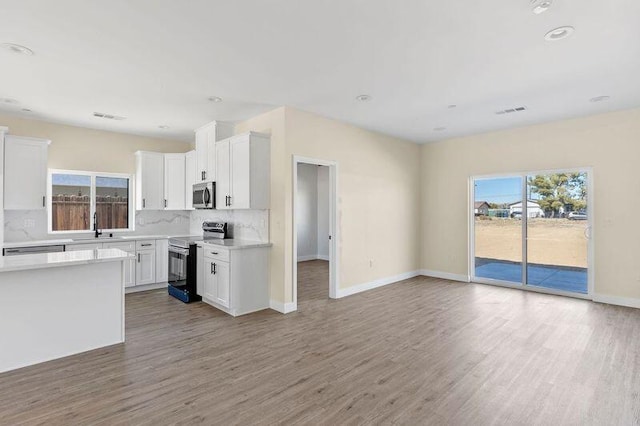 kitchen featuring white cabinetry, sink, hardwood / wood-style floors, decorative backsplash, and appliances with stainless steel finishes