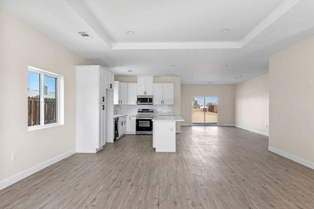 kitchen featuring white cabinets, a kitchen island, a healthy amount of sunlight, and appliances with stainless steel finishes