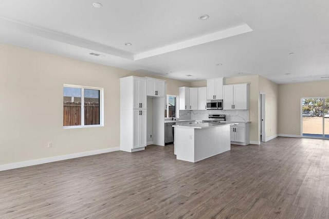 kitchen featuring a center island, decorative backsplash, white cabinetry, wood-type flooring, and stainless steel appliances