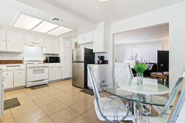 44605 Gillan Ave, Lancaster, CA 93535 - kitchen featuring white range with gas cooktop, freestanding refrigerator, black microwave, under cabinet range hood, and white cabinetry