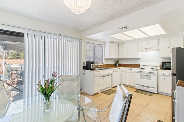 44605 Gillan Ave, Lancaster, CA 93535 - kitchen featuring white appliances, under cabinet range hood, plenty of natural light, white cabinetry, and a textured ceiling