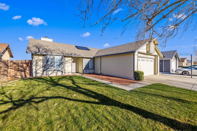 single story home featuring concrete driveway, an attached garage, fence, roof mounted solar panels, and a front yard