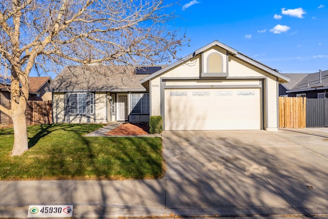 ranch-style house featuring driveway, an attached garage, fence, roof mounted solar panels, and a front yard