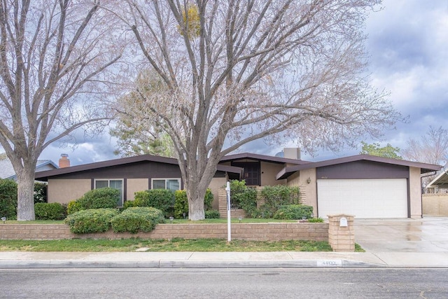 view of front of home with an attached garage, a chimney, and stucco siding