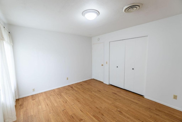 unfurnished bedroom with light wood finished floors, a closet, visible vents, and baseboards