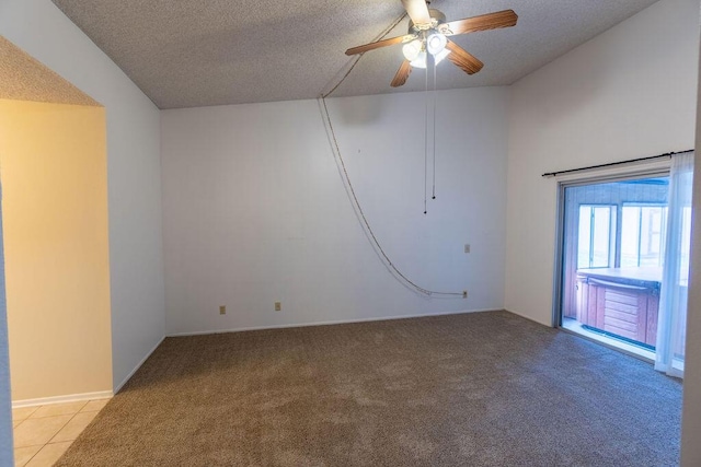 spare room featuring a ceiling fan, light carpet, a textured ceiling, and light tile patterned floors