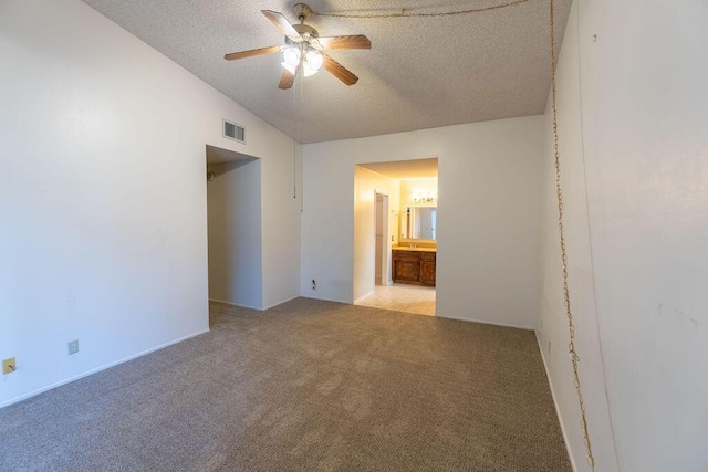 unfurnished bedroom featuring ensuite bath, visible vents, a textured ceiling, and light colored carpet