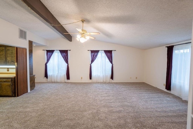 empty room featuring carpet, a healthy amount of sunlight, vaulted ceiling with beams, and visible vents