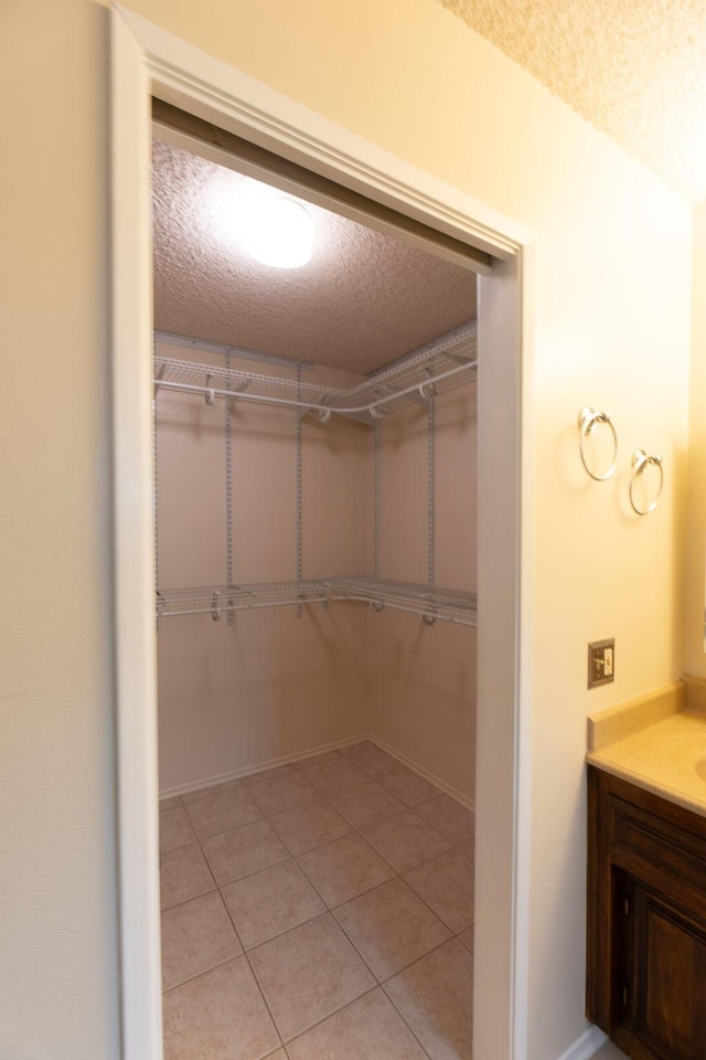 walk in closet with light tile patterned floors