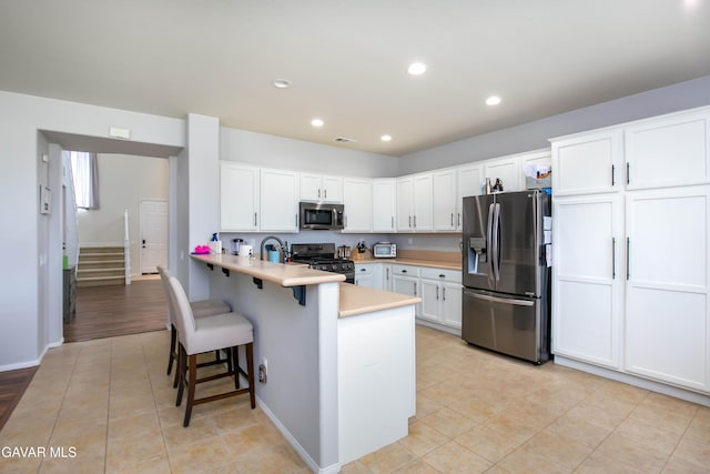 44927 Normandy Ln, Lancaster, CA 93536 - kitchen featuring stainless steel appliances, a peninsula, a breakfast bar area, light countertops, and light tile patterned floors