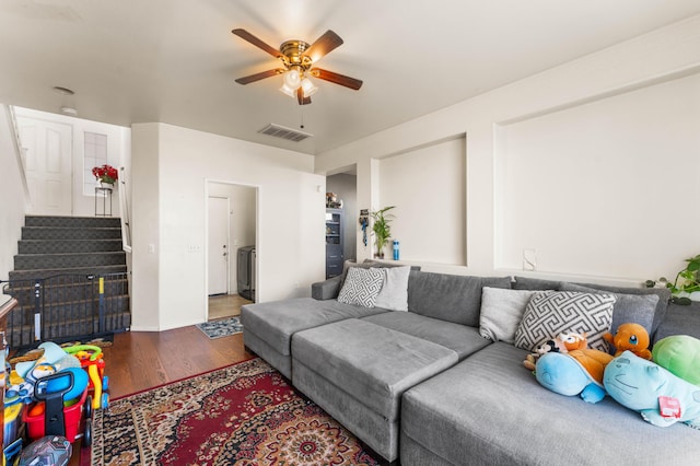 living room with ceiling fan and dark wood-type flooring