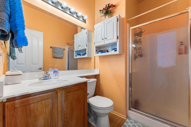 bathroom featuring vanity, toilet, wood-type flooring, and walk in shower