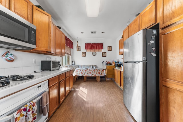 kitchen with tile countertops, light hardwood / wood-style floors, and stainless steel appliances