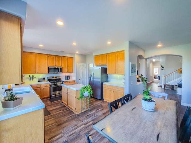 kitchen featuring appliances with stainless steel finishes, light countertops, arched walkways, and a center island