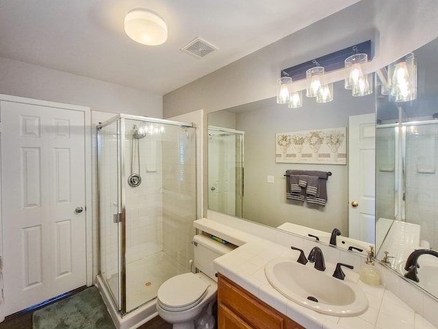 bathroom featuring toilet, a shower stall, visible vents, and vanity