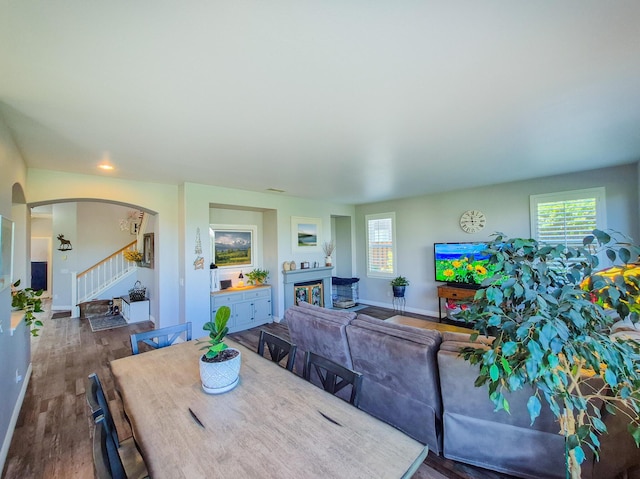 dining space with a healthy amount of sunlight, dark wood-style floors, stairway, and arched walkways