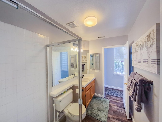 full bath with visible vents, tiled shower, wood finished floors, and vanity