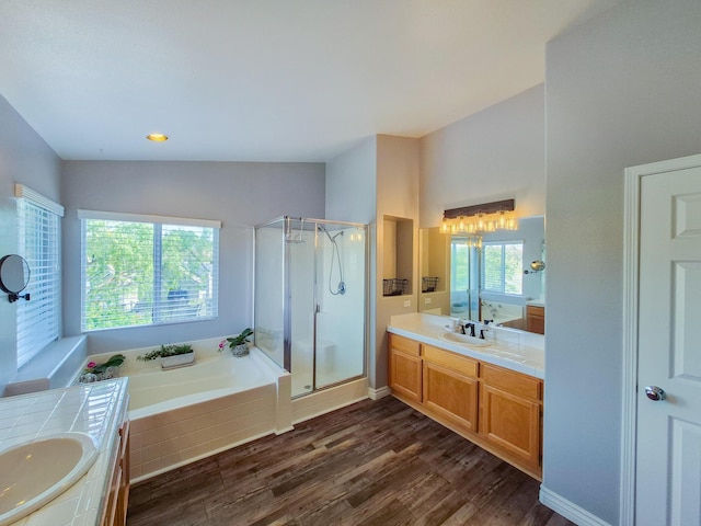 bathroom with a garden tub, a sink, wood finished floors, two vanities, and a shower stall