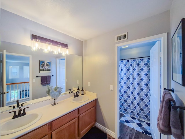 full bath featuring double vanity, a sink, and wood finished floors