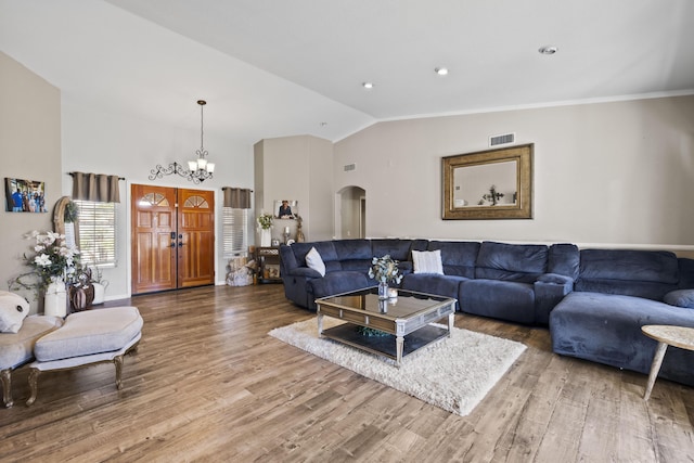 living room featuring vaulted ceiling, a notable chandelier, ornamental molding, and hardwood / wood-style floors