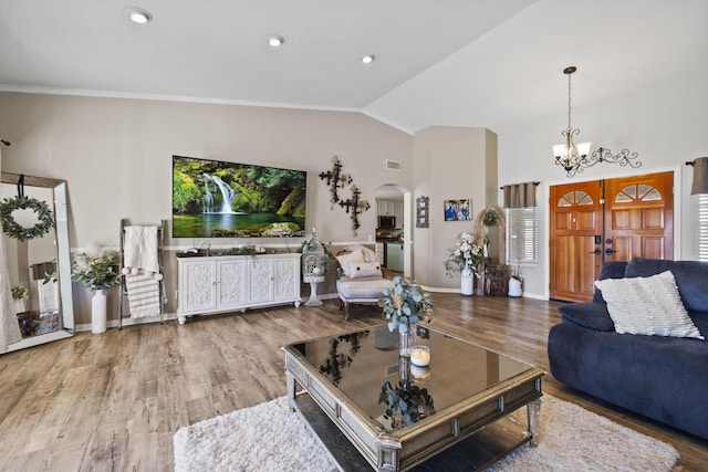 living room with vaulted ceiling, an inviting chandelier, ornamental molding, and hardwood / wood-style floors