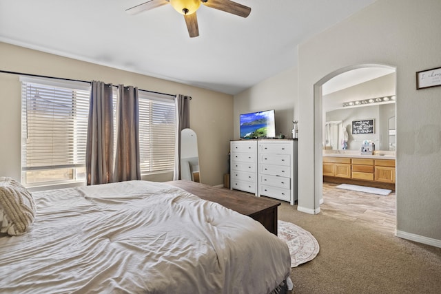 carpeted bedroom featuring vaulted ceiling, ceiling fan, and ensuite bath