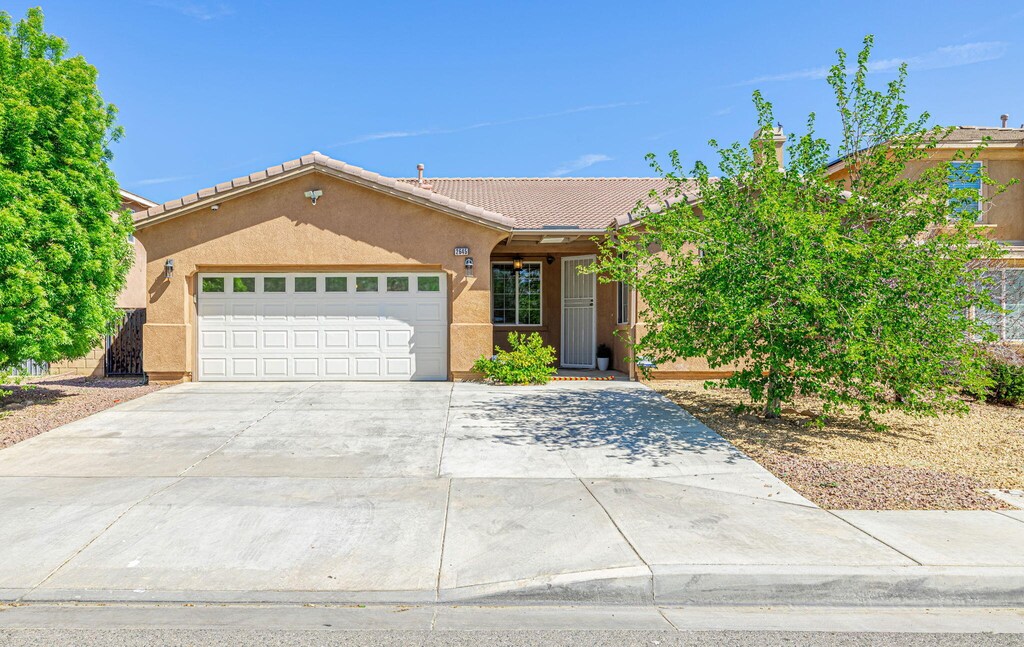 2645 E Nugent St, Lancaster, CA 93535 - ranch-style house with a tile roof, an attached garage, concrete driveway, and stucco siding