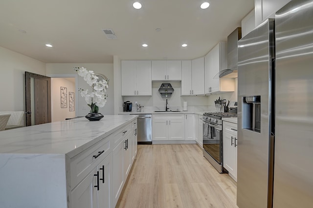 12871 W Osborne St, Arleta, CA 91331 - kitchen featuring stainless steel appliances, wall chimney range hood, light wood-type flooring, light stone counters, and a kitchen island