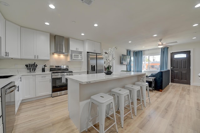 12871 W Osborne St, Arleta, CA 91331 - kitchen with wall chimney range hood, appliances with stainless steel finishes, a kitchen island, a kitchen breakfast bar, and recessed lighting