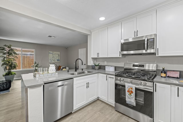 kitchen featuring white cabinetry, appliances with stainless steel finishes, sink, and kitchen peninsula