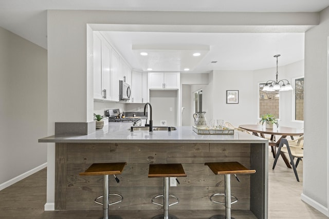 kitchen featuring white cabinetry, a kitchen bar, sink, and appliances with stainless steel finishes