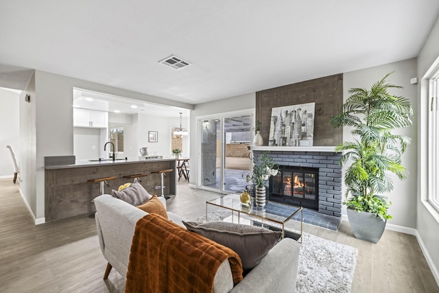 living room featuring sink, a fireplace, and light hardwood / wood-style floors