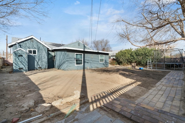 rear view of house with a patio area and a trampoline