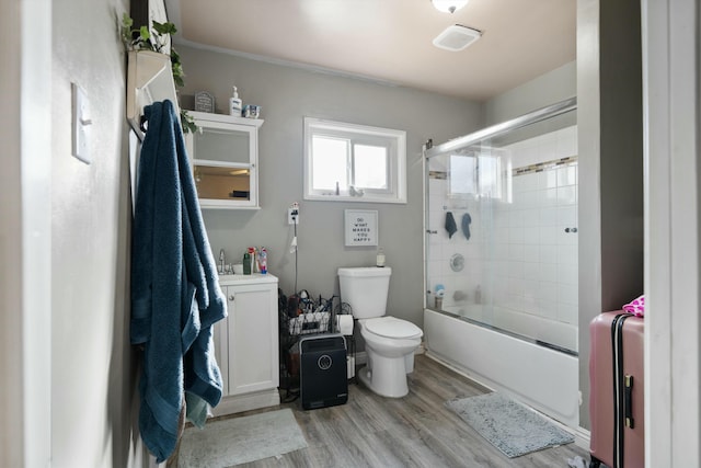 full bathroom with sink, hardwood / wood-style floors, bath / shower combo with glass door, and toilet