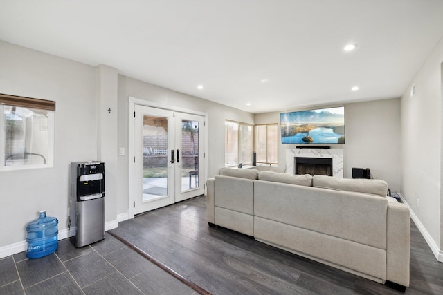 living room featuring french doors, dark wood-type flooring, and a premium fireplace