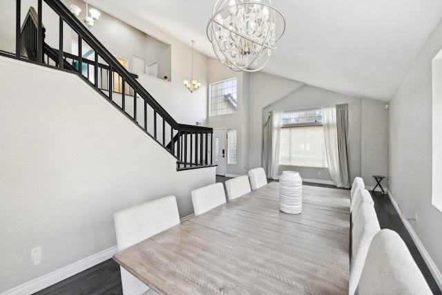 dining space with hardwood / wood-style floors, a towering ceiling, and a notable chandelier