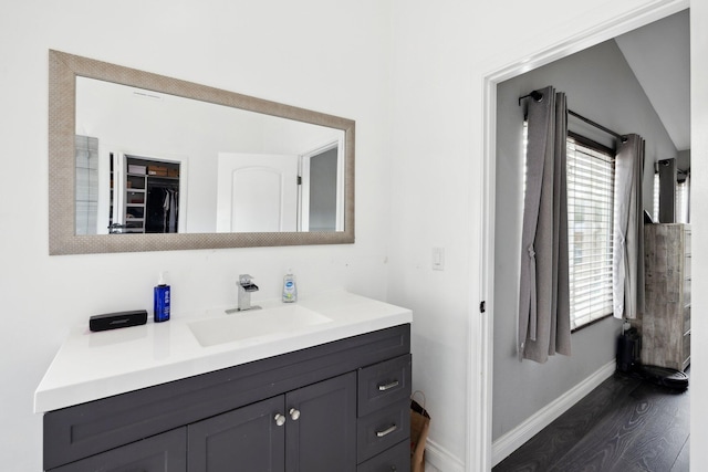 bathroom featuring wood-type flooring, vanity, vaulted ceiling, and a healthy amount of sunlight