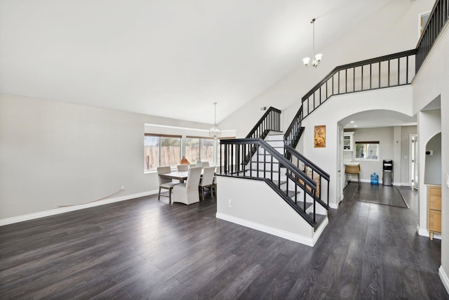 stairs with a towering ceiling, hardwood / wood-style flooring, and a notable chandelier