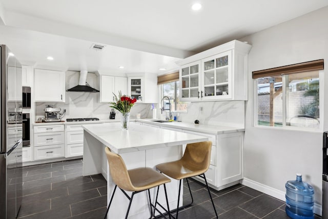 kitchen with white cabinets, custom range hood, sink, and tasteful backsplash