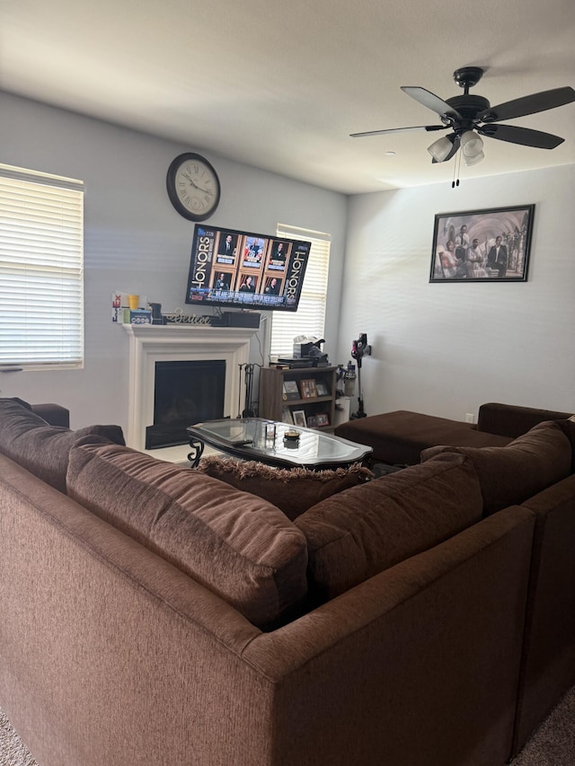 living area featuring a fireplace and a ceiling fan