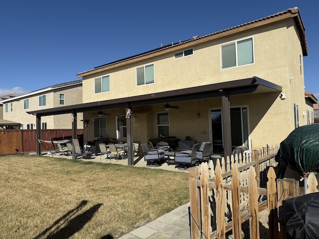 back of house featuring fence, a ceiling fan, a yard, stucco siding, and a patio area