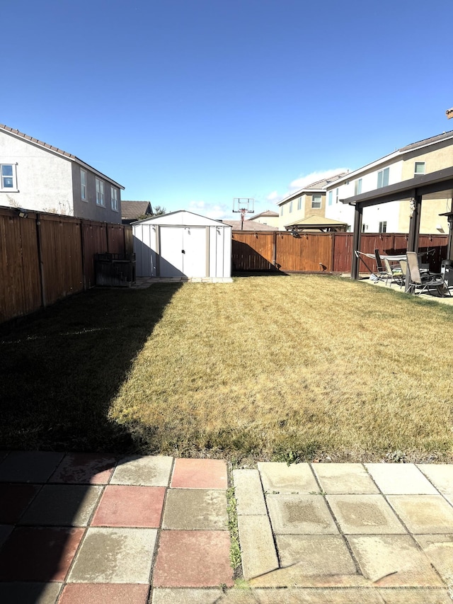 view of yard with an outbuilding, a storage unit, a patio area, and a fenced backyard