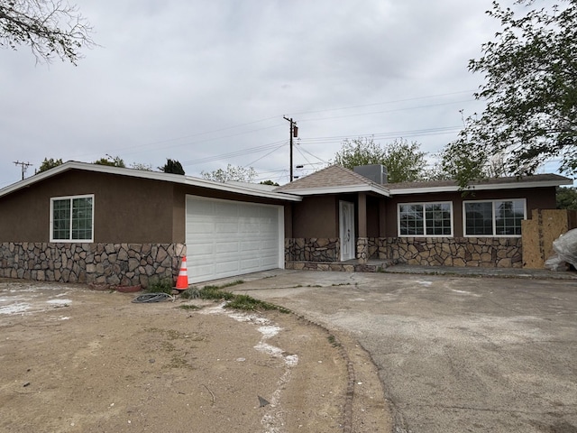 single story home with a garage, stucco siding, roof with shingles, stone siding, and concrete driveway