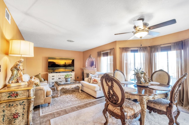 dining room with tile patterned floors, visible vents, a textured ceiling, and a ceiling fan