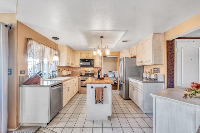 kitchen featuring a notable chandelier, a sink, a kitchen island, appliances with stainless steel finishes, and a raised ceiling