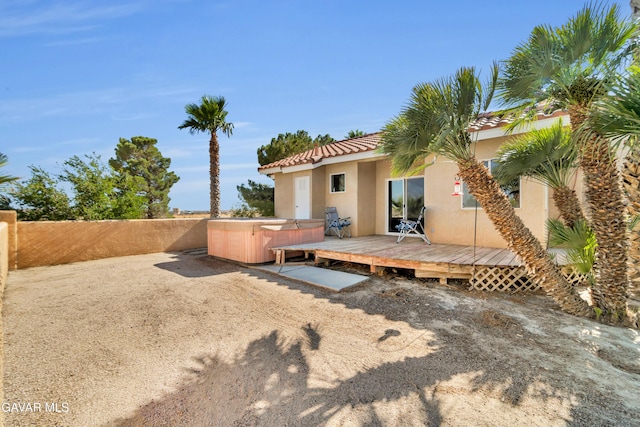 8433 Prospect St, Mojave, CA 93501 - rear view of property with a hot tub, stucco siding, a wooden deck, a tiled roof, and a fenced backyard