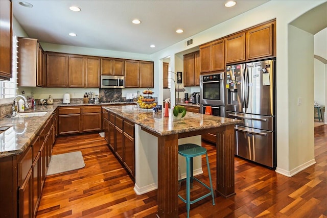 kitchen featuring light stone counters, sink, a kitchen island, and appliances with stainless steel finishes