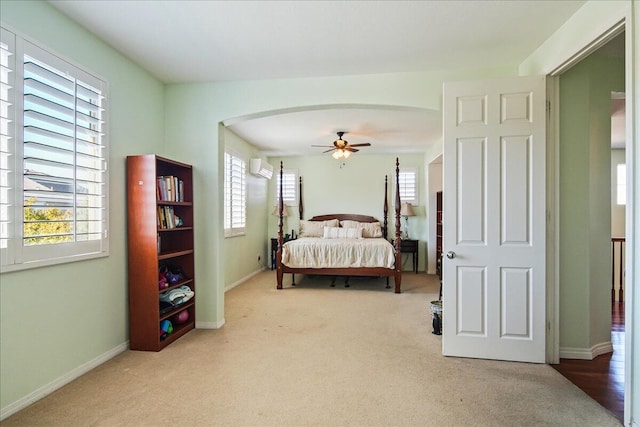 carpeted bedroom with ceiling fan, a wall mounted AC, and multiple windows