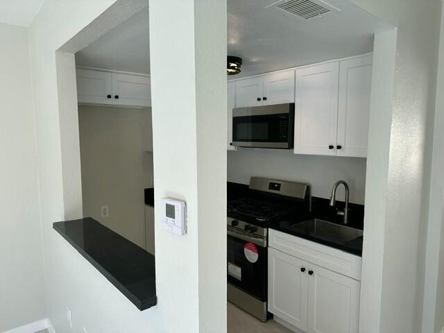 kitchen with sink, white cabinetry, and stainless steel appliances