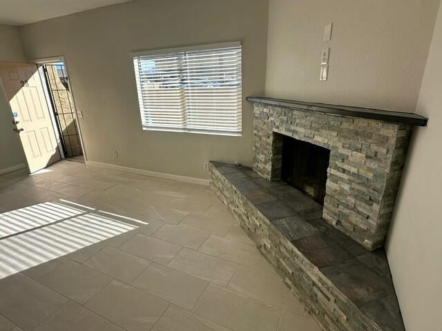 unfurnished living room featuring tile patterned flooring and a stone fireplace